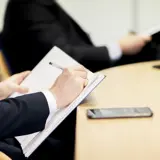A graphic image of a person writing in a notepad, Aaron Wallis Sales Recruitment